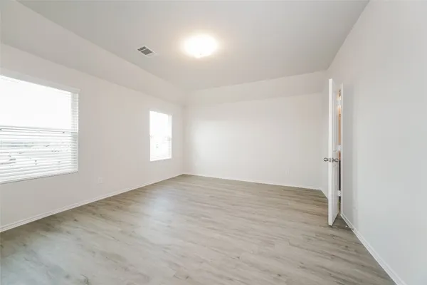 an empty room with wooden floor and windows