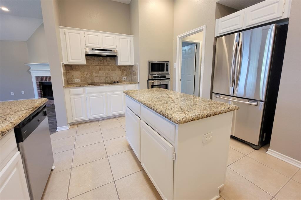 1604 Knoll Ridge Circle Corinth, TX 76210 - Photo 19 of 37 Spacious kitchen featuring an island with granite-finish countertop, white cabinetry, stainless steel appliances, and tile flooring