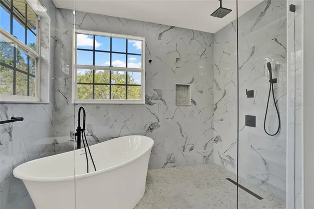 a bathroom with a white bath tub sitting next to a window