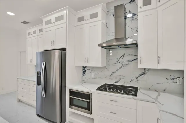 a kitchen with stainless steel appliances granite countertop a refrigerator a stove and white cabinets with wooden floor