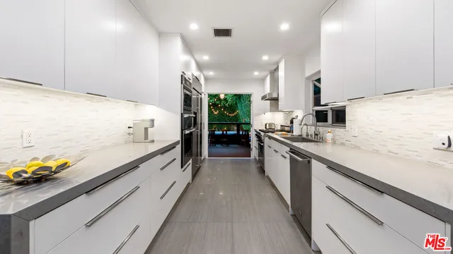 a large kitchen with stainless steel appliances a large counter top a stove and a sink