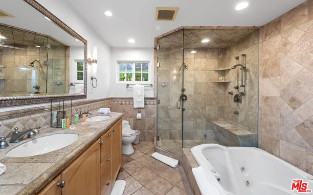 a bathroom with a bathtub shower sink mirror and toilet
