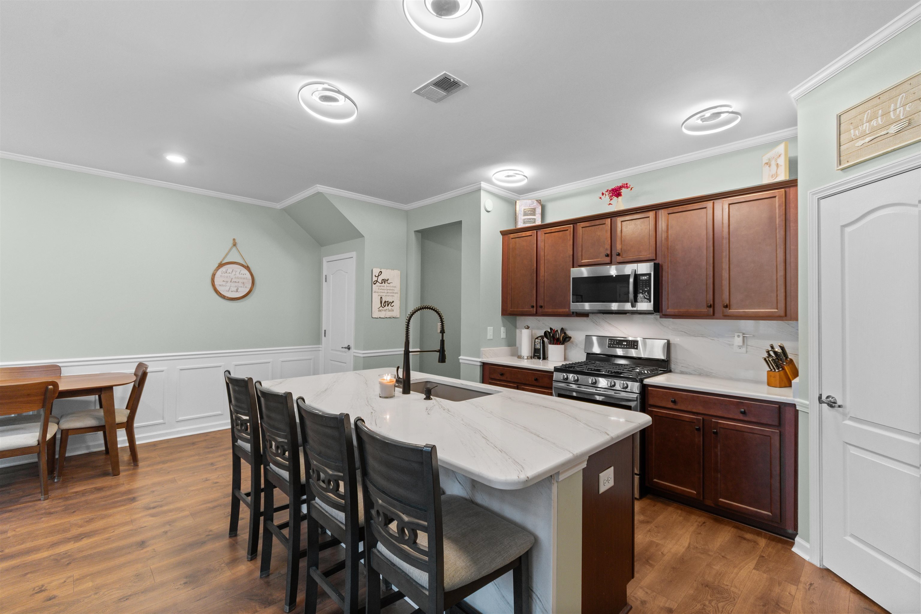 2408 Heritage Loop, Unit 2408 Myrtle Beach, SC 29577 - Photo 4 of 40 Kitchen featuring a breakfast bar area, stainless steel appliances, light stone counters, a center island with sink, and wainscoting