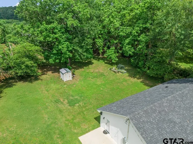 a view of barn house with a small yard plants and large trees