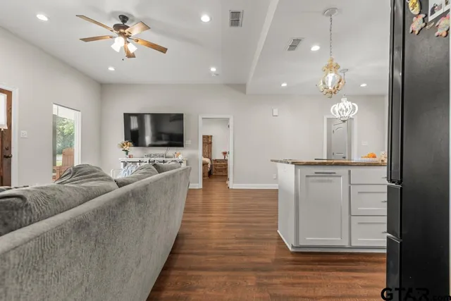 a living room with furniture a flat screen tv and kitchen view