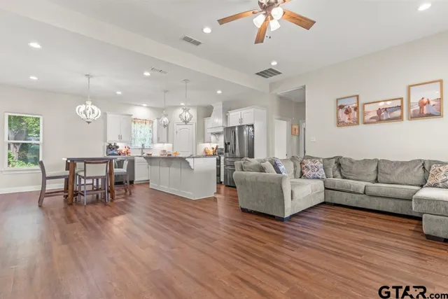 a living room with furniture and a dining table with wooden floor