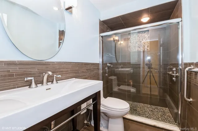 a bathroom with a sink a toilet a mirror and shower