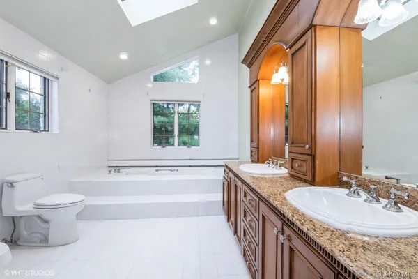 a bathroom with a granite countertop sink a toilet a mirror and a bathtub
