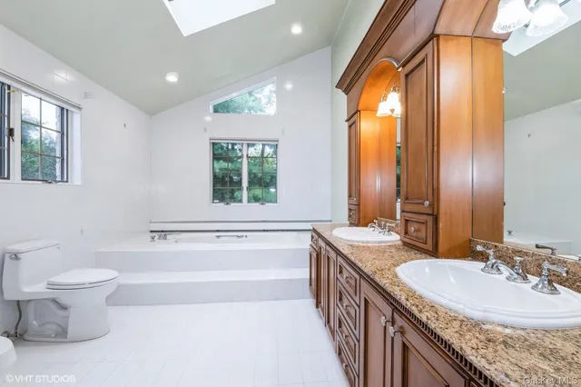 a bathroom with a granite countertop sink a toilet a mirror and a bathtub