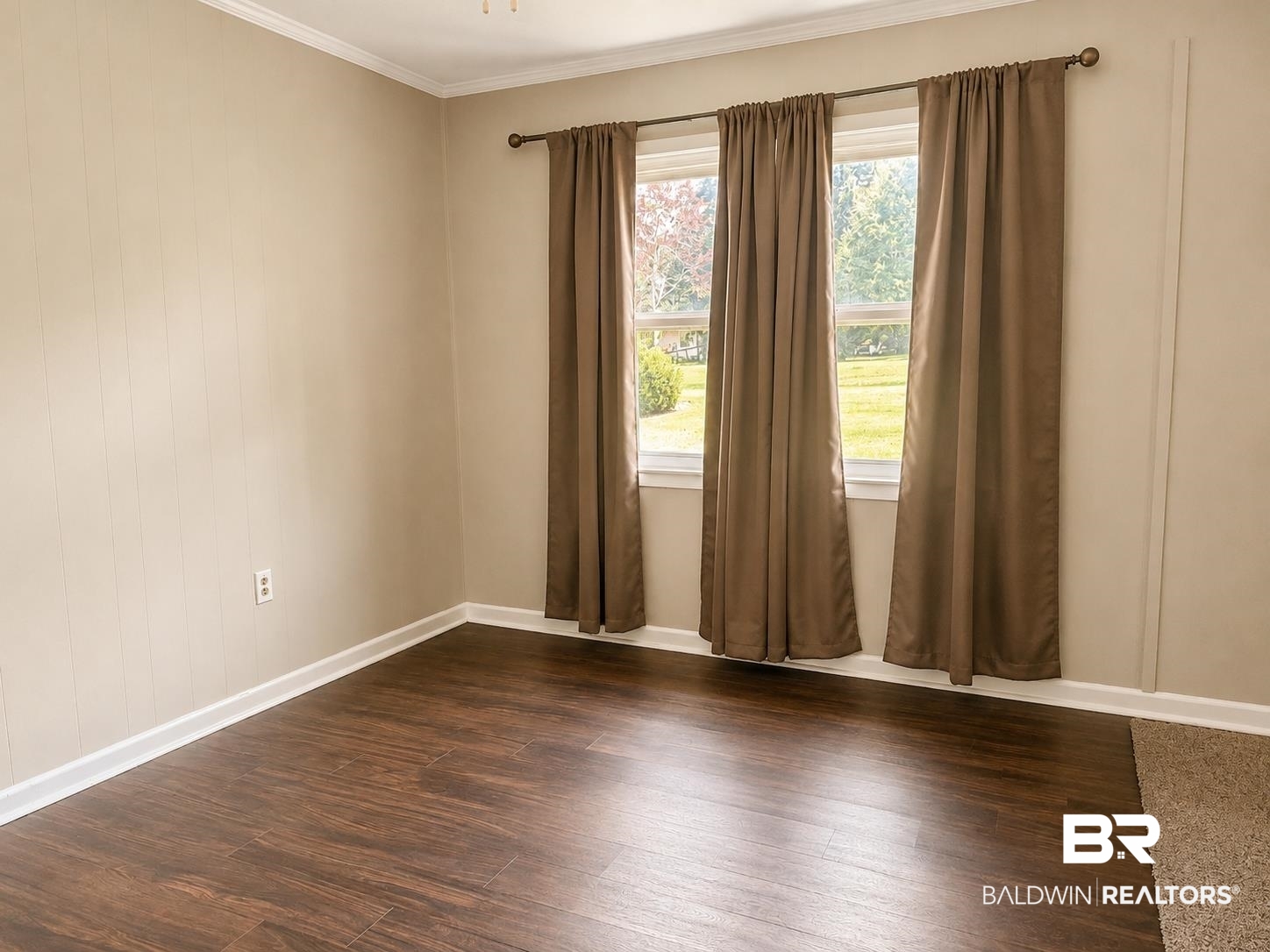 11115 Appleton Road Castleberry, AL 36432 - Photo 4 of 18 Room featuring wood-finish flooring, two large windows, neutral wall paneling, and white trim