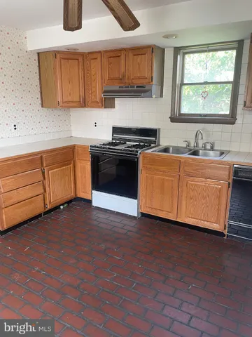 a kitchen with stainless steel appliances granite countertop a sink a stove a refrigerator with grey cabinets and wooden floor