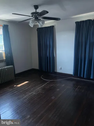 a view of an empty room with a ceiling fan and wooden floor