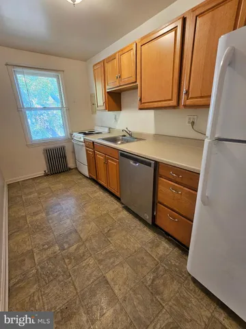 a kitchen with granite countertop a sink cabinets stainless steel appliances and a window