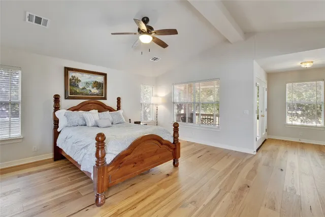 a spacious bedroom with a large bed chandelier and a window