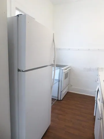 a view of a refrigerator in kitchen and empty room
