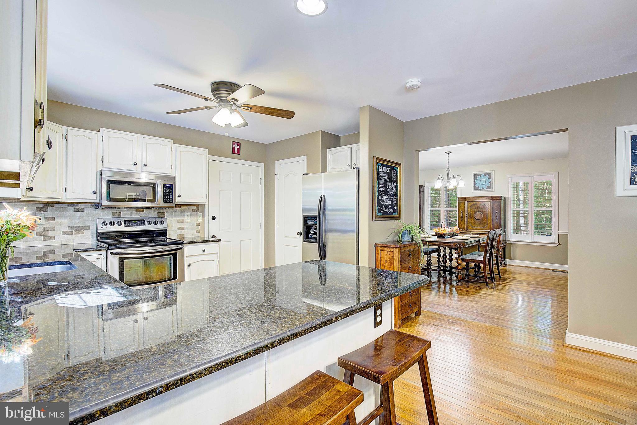 205 Walnut Creek Road Huntingtown, MD 20639 - Photo 16 of 48 a kitchen with stainless steel appliances granite countertop a stove a refrigerator a oven a sink a dining table and chairs with wooden floor