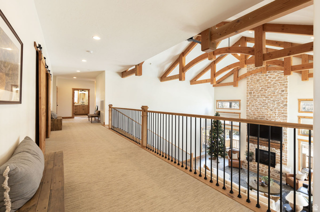 382 Ridgeview Street, Unit 8 & 9 Brian Head, UT 84719 - Photo 21 of 52 Upper-level hallway overlooking a great room featuring vaulted ceilings with exposed wood beams, a stone fireplace, and a light wood railing with black spindles