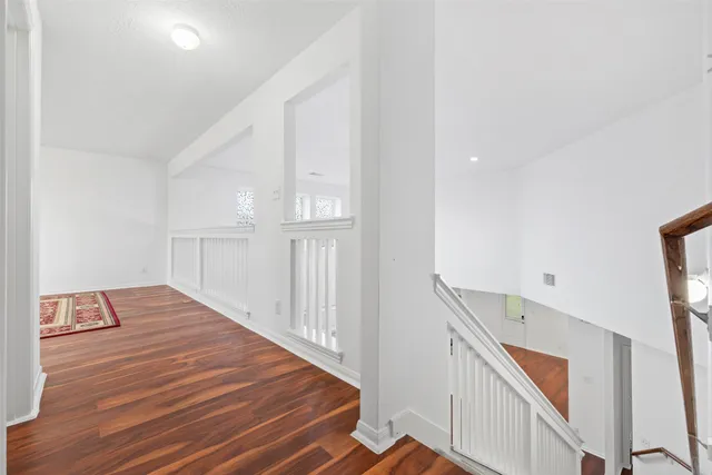 a view of an empty room with window and wooden floor