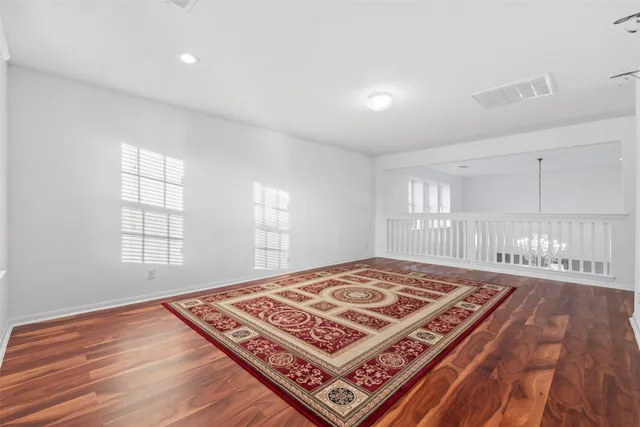 an empty room with wooden floor fan and windows