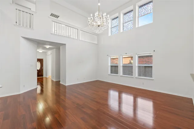 a view of an empty room with wooden floor and a chandelier