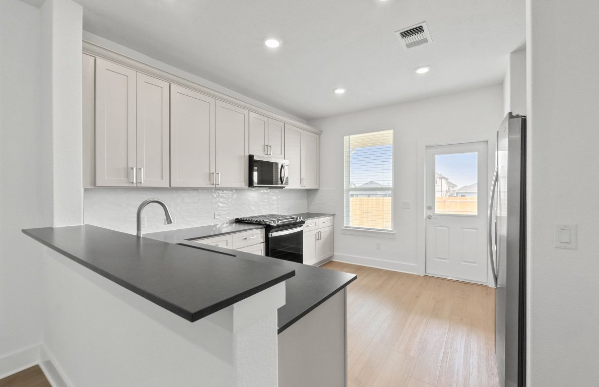 494 Tailwind Drive Kyle, TX 78640 - Photo 10 of 34 a kitchen with stainless steel appliances granite countertop a sink a stove and a refrigerator