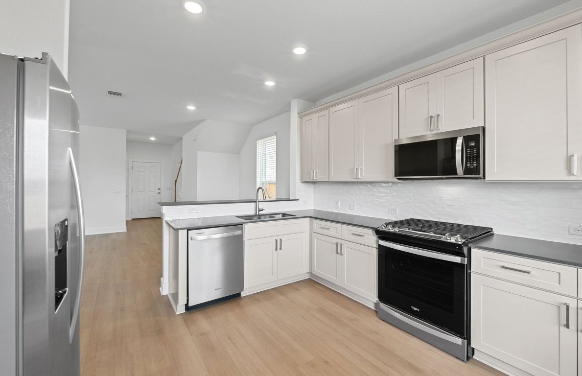 494 Tailwind Drive Kyle, TX 78640 - Photo 11 of 34 a kitchen with stainless steel appliances granite countertop a stove a sink and a refrigerator