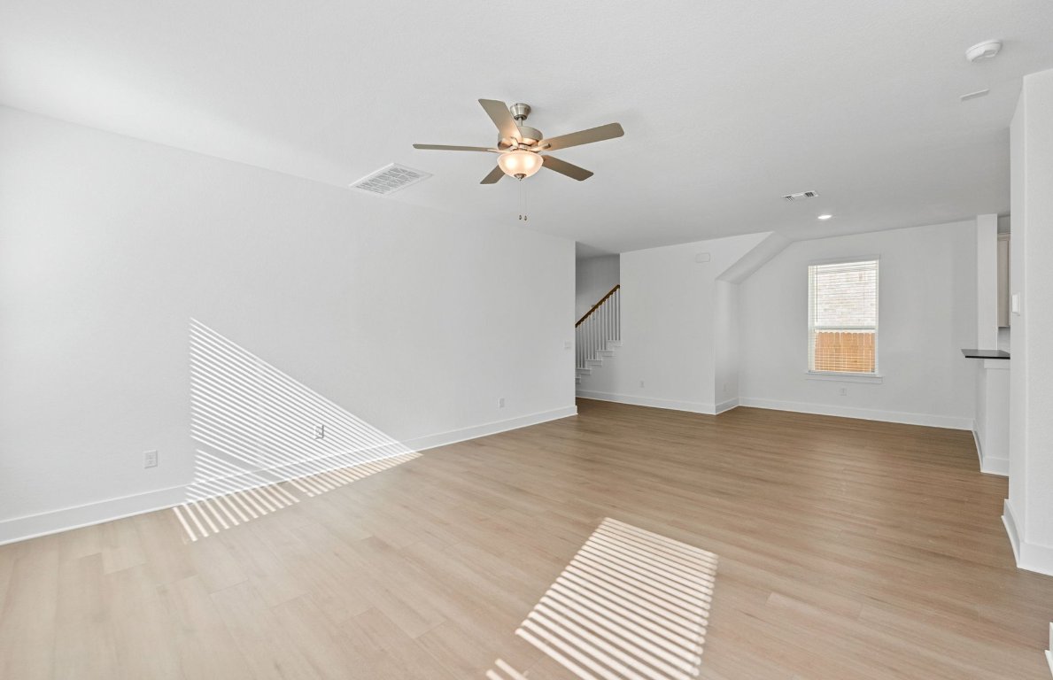 494 Tailwind Drive Kyle, TX 78640 - Photo 8 of 34 an empty room with wooden floor ceiling fan and windows