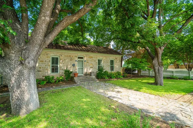 a view of a house with a yard and a large tree