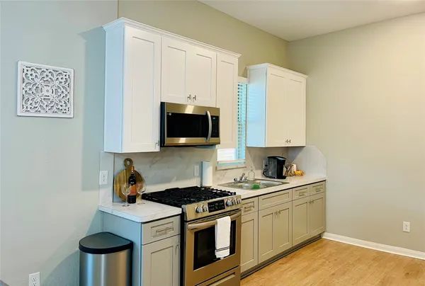 a kitchen with stainless steel appliances a stove a microwave a sink and cabinets