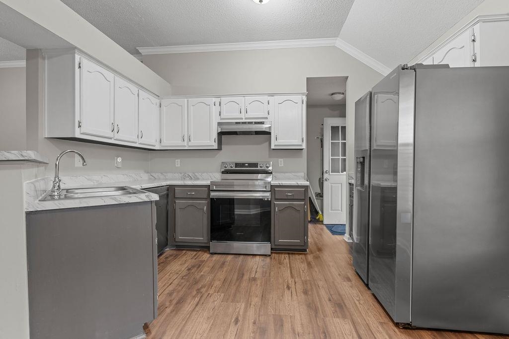 5340 Shady Ridge Cove Memphis, TN 38141 - Photo 6 of 22 Kitchen featuring stainless steel appliances, a textured ceiling, gray cabinets, wood finished floors, and ornamental molding