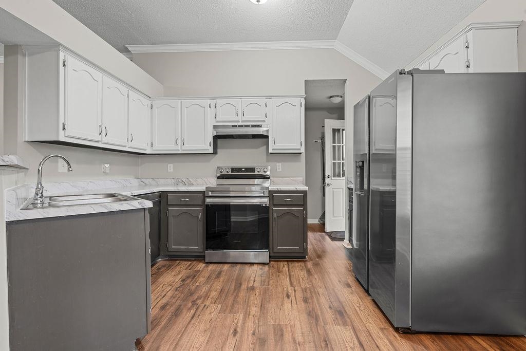 5340 Shady Ridge Cove Memphis, TN 38141 - Photo 7 of 22 Kitchen featuring stainless steel appliances, a textured ceiling, dark wood-style floors, crown molding, and white cabinets