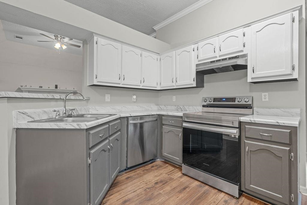 5340 Shady Ridge Cove Memphis, TN 38141 - Photo 8 of 22 Kitchen featuring appliances with stainless steel finishes, gray cabinets, wood finished floors, light countertops, and under cabinet range hood