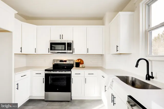a kitchen with white cabinets a sink and a stove with wooden floor
