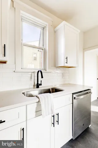 a kitchen with white cabinets and sink