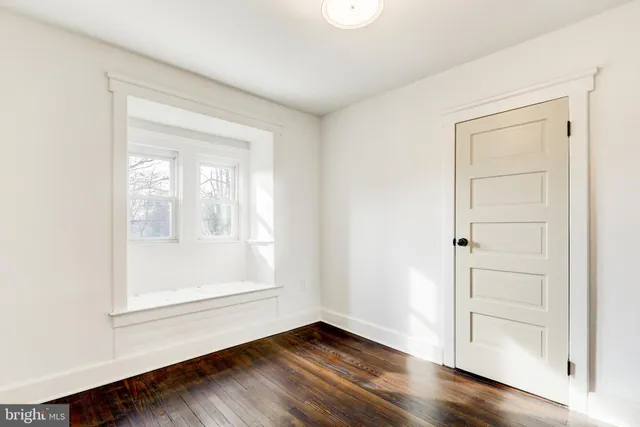 an empty room with wooden floor cabinet and windows