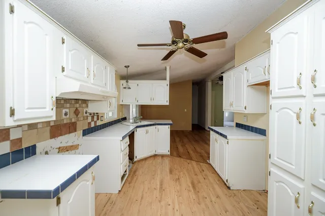 a kitchen with stainless steel appliances a stove top oven a sink a refrigerator white cabinets and wooden floor