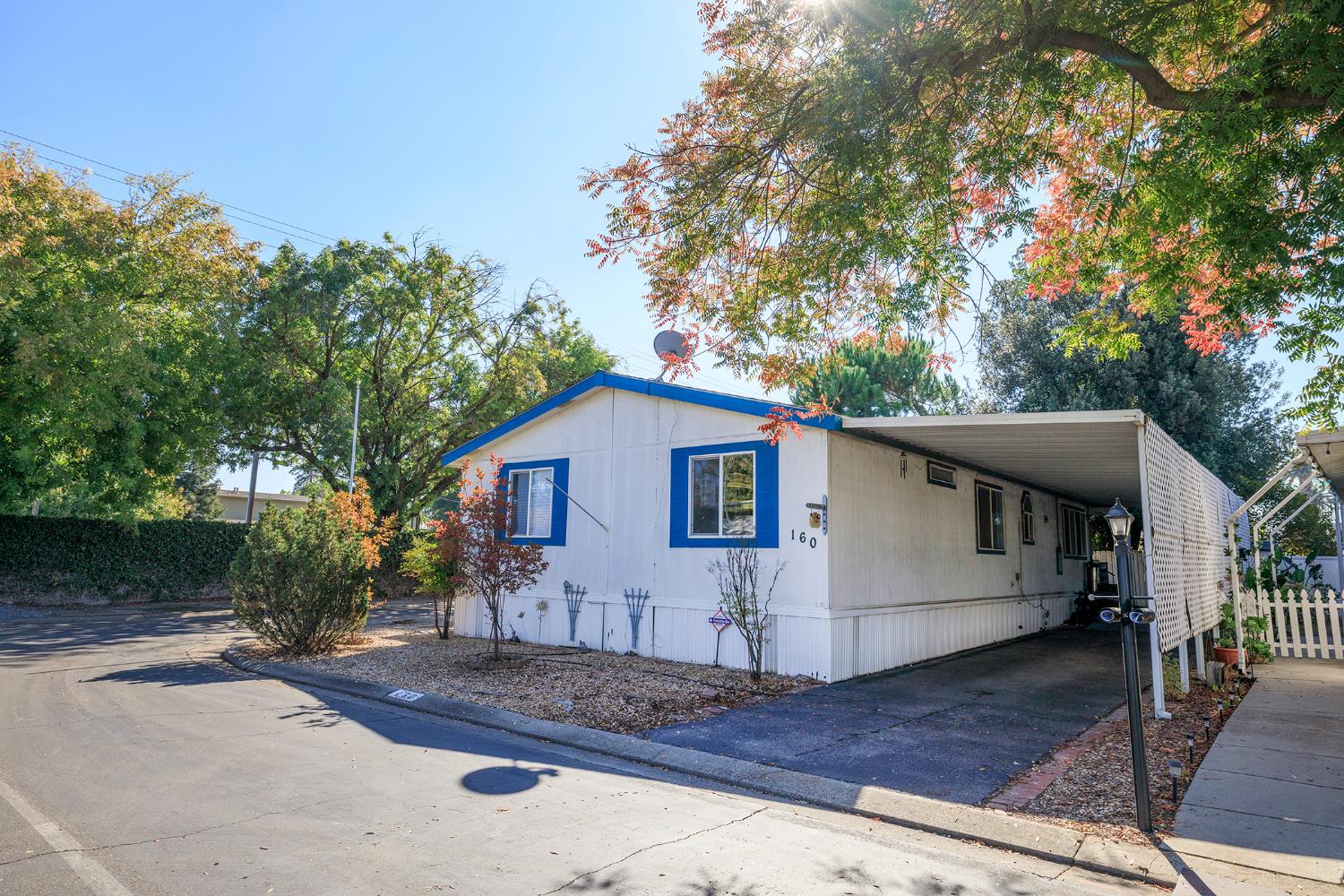 2621 Prescott Road, Unit 160 Modesto, CA 95350 - Photo 2 of 37 a view of a small white house with large tree and wooden fence