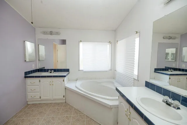 a bathroom with a granite countertop bathtub a sink and a mirror