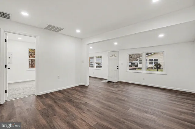 an empty room with wooden floor and white walls