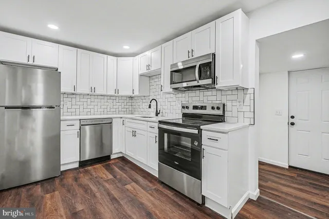 a kitchen with white cabinets stainless steel appliances and a refrigerator