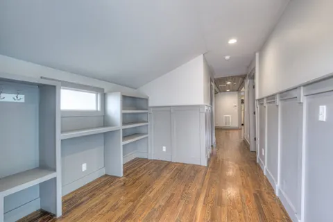 a view of a hallway with wooden floor and closet area