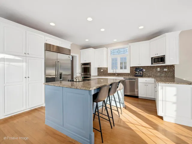 a kitchen with stainless steel appliances granite countertop a stove top oven a sink dishwasher and a refrigerator with wooden floor