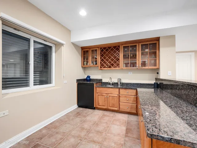a large kitchen with granite countertop a sink window and cabinets