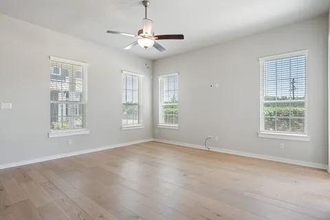 a view of an empty room with a window and wooden floor