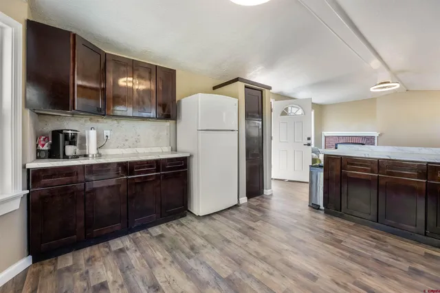 a kitchen with stainless steel appliances granite countertop a refrigerator a stove a sink and dishwasher with wooden floor