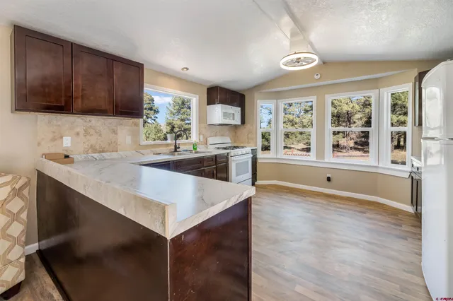 a large kitchen with granite countertop a sink and a stove top oven with wooden floor