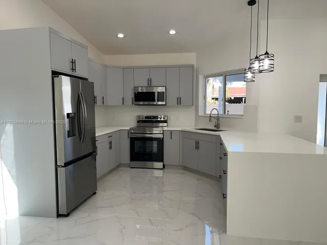 a kitchen with stainless steel appliances a refrigerator a sink a stove a microwave a center island and cabinets