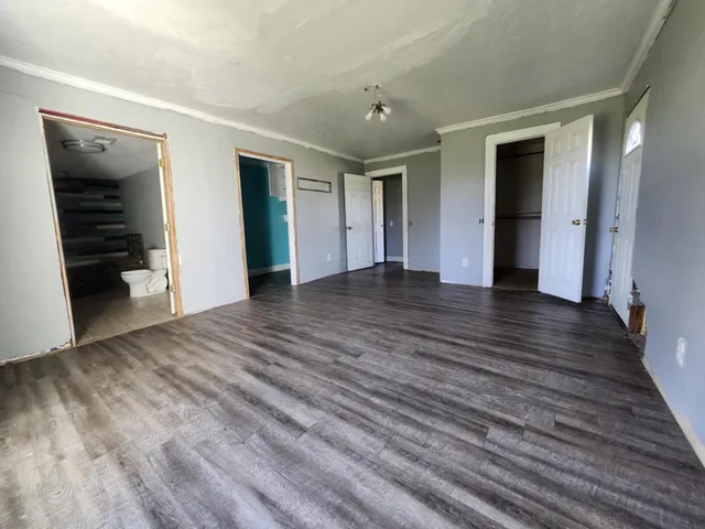 a view of an empty room with wooden floor and closet