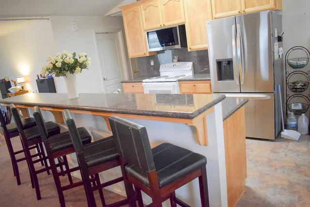 a kitchen with stainless steel appliances kitchen island granite countertop furniture and a refrigerator
