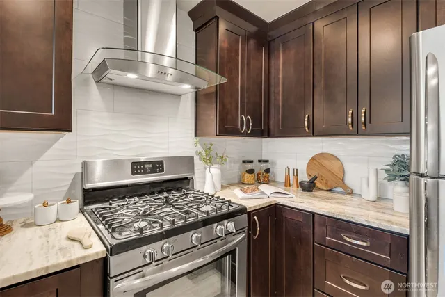 a kitchen with granite countertop stainless steel appliances stove top oven and cabinets
